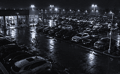 Night camera view of rows of parked cars on a dealership lot