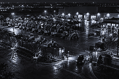 Night camera view of an equipment rental yard with parked machines