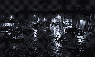 Night camera view of a farm yard with tractors and a machinery barn