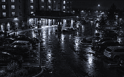 Night camera view of a hotel entrance and guest parking