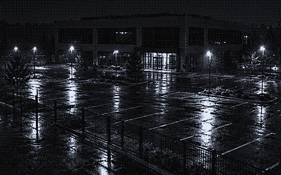 Night camera view of a vacant office building and empty fenced lot